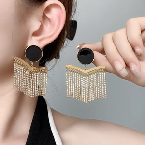 Macro detail of luxury gold tassel earrings with black enamel and sparkling rhinestones
