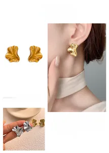 Detailed view of irregular wavy gold and silver stud earrings with liquid metal texture