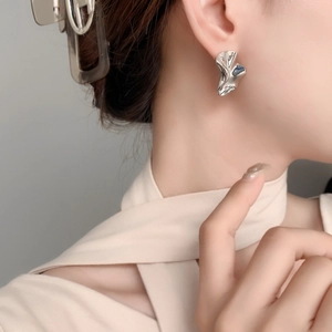 Irregular textured silver stud earrings with molten lava design worn by a model