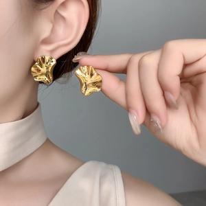 Close-up of irregular pleated gold earrings with a polished mirror finish on model