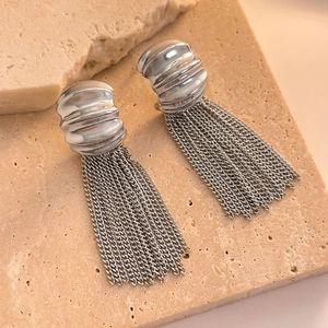 Detail shot of silver fringe earrings with metallic chain tassels on a textured stone