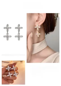 Detail of silver clover drop earrings with sparkling cubic zirconia on model and hand