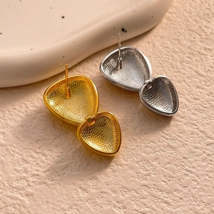 Detailed close-up of heart stud earrings with mirror finish and inner beaded texture