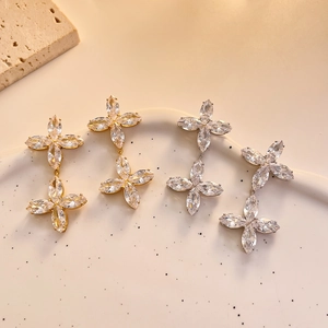 Macro detail of gold and silver four-leaf clover stud earrings with marquise zircons