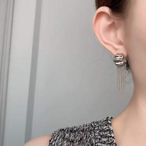 Detail shot of silver tassel earrings with textured buckle and metallic snake chains