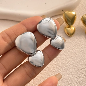 Close-up of dual heart-shaped drop earrings with high-polish mirror finish and 18K plating