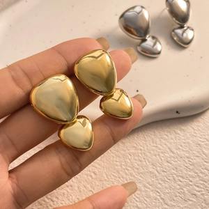 Macro detail of high-polish 18K gold-plated heart earrings showing mirror finish