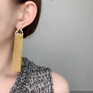 Gros plan de boucles d'oreilles pendantes dorées avec zircons portées par un mannequin