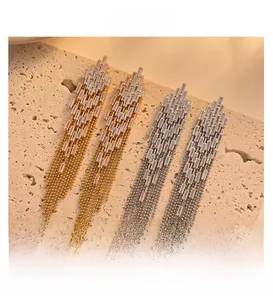 Detail of 18K gold and silver tassel earrings with zircon studs on stone background