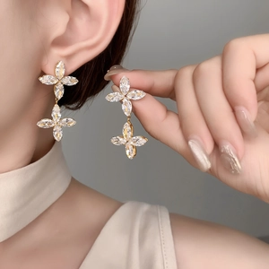 Detail of elegant gold double clover earrings with zircon marquise stones on a model