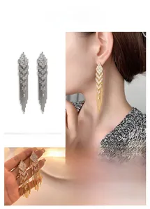 Detailed close-up of long tassel earrings with sparkling zircon and 18K gold plating