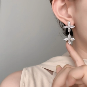 Detail of double cross clover earrings with marquise-cut zircons on a model