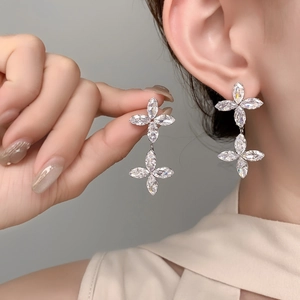 Macro detail of silver marquise zircon flower drop earrings worn on a model ear