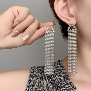 Détail de longues boucles d'oreilles pampilles argentées avec strass brillants et chaînettes