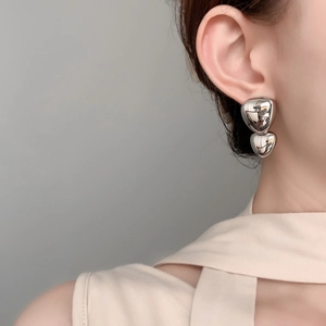 Close-up of shiny silver double heart earrings featuring high-polish mirror finish metal