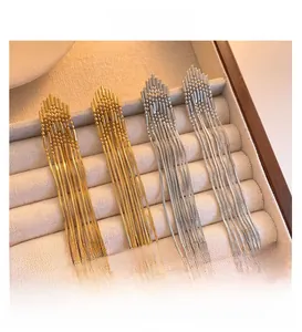 Detail of long chain tassel earrings in gold and silver finish on velvet display