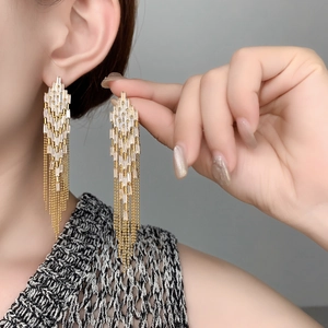 Macro detail of 18K gold-plated tassel earrings featuring tiered zirconia crystals