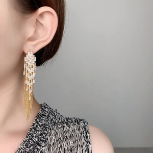 Macro detail of long gold tassel earrings with zircon rectangular crystal settings
