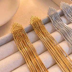 Elegant 18K gold and silver long tassel chain drop earrings on a light jewelry tray