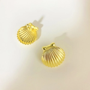 Macro detail of gold-plated shell earrings showing vertical textured relief patterns