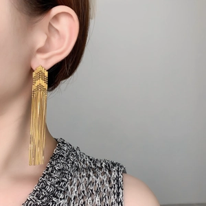 Detail view of long gold tassel earrings on a model showing elegant drape and metallic shine