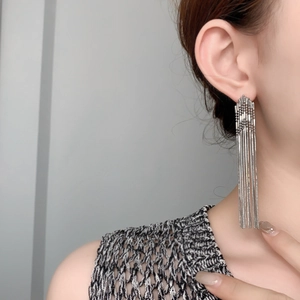 Detailed view of silver long chain tassel earrings worn by a model for elegant styling