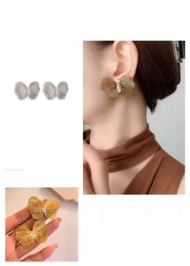 Detailed view of large hollow butterfly stud earrings with fine wire texture and crystals