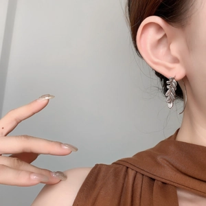 Artistic silver leaf drop earrings with delicate veins on a female model for a nature-inspired look