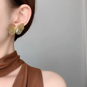 Macro view of gold butterfly stud earring featuring hollow texture and central zircon