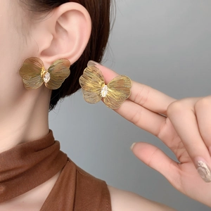 Detailed close-up of hollow butterfly earrings with gold plating and teardrop zirconia