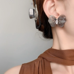 Detail shot of vintage hollow butterfly earrings featuring a teardrop crystal accent