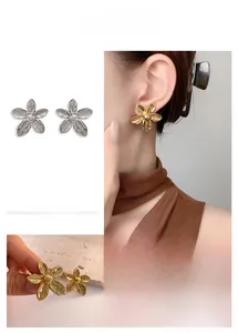 Detailed view of floral stud earrings in 18K gold and silver with textured metal petals