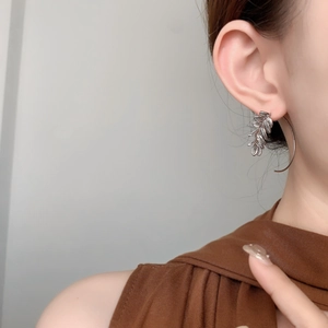 Close-up of silver leaf layered earrings with a delicate curved wire on model