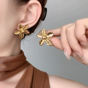 Detailed view of elegant 18K gold plated flower earrings on model with metallic petals