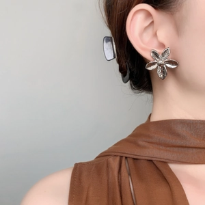Close-up of elegant flower stud earring in polished finish on female model ear