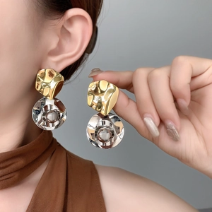 Boucles d'oreilles plissées or et argent portées pour montrer les détails et la texture