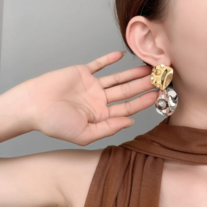 Gros plan de boucles d'oreilles bicolores irrégulières avec texture martelée et perle