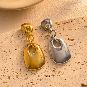 Detailed close-up of 18K gold and silver geometric square drop earrings on stone base