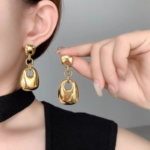 Detailed view of large gold geometric hollow drop earrings with 18K plating on a model