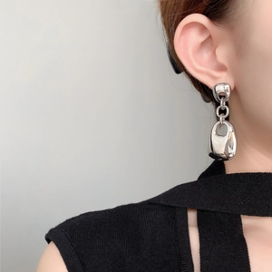 Detail of silver geometric dangling earrings with high polish finish on a female model