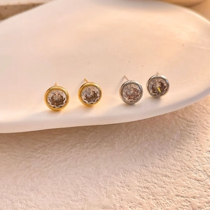 Nahaufnahme minimalistischer Gold- und Silber-Ohrstecker mit großen klaren Zirkoniasteinen