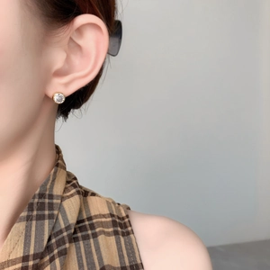 Eleganter vergoldeter Ohrstecker mit großem rundem Zirkon, am weiblichen Ohr getragen