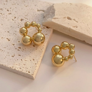 Detail of gold beaded hoop earrings with gradient spherical design on stone
