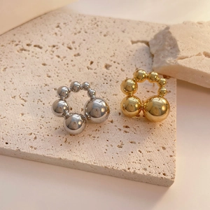 Detail of beaded metal stud earrings in gold and silver finish on stone base