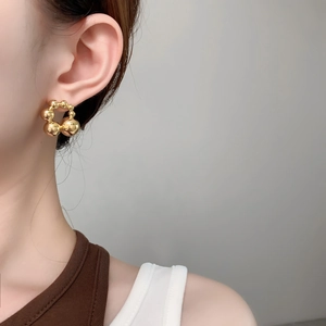 Macro detail of high-shine gold beaded sphere earrings showing reflective metallic texture
