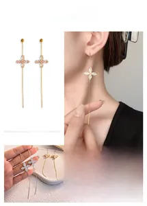Detail of long tassel earrings with 18K gold plating and four-leaf clover zircon stud