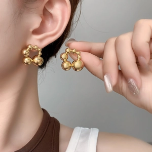 Detailed view of polished golden ball cluster stud earrings showing metallic shine