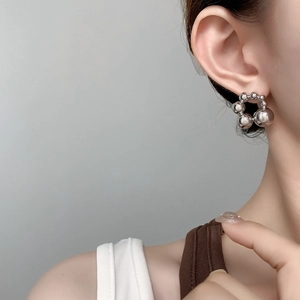Close-up of polished silver beaded hoop earrings worn on a model's ear for size reference
