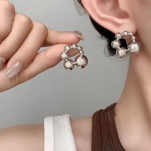 Close-up of polished silver spherical bead hoop earrings on model for a modern metallic look