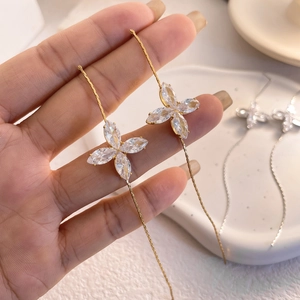 Macro view of long chain drop earrings with 18K gold plating and zircon clover motifs